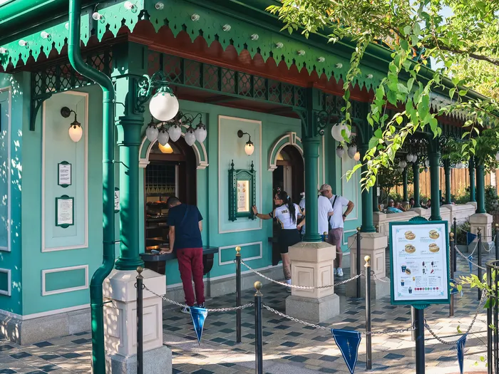 Counter of La Terrasse Panoramique at Disneyland Paris, green facade, customers ordering in front of the displayed menus