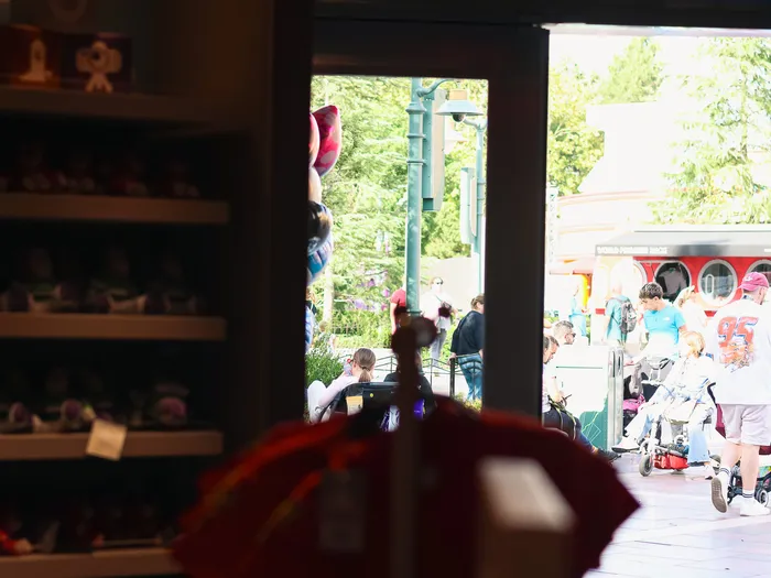 Exit of the Animation Boutique at Disneyland Paris: from the dim aisles, the door opens onto the sunny walkway and the World Premiere Snacks kiosk.