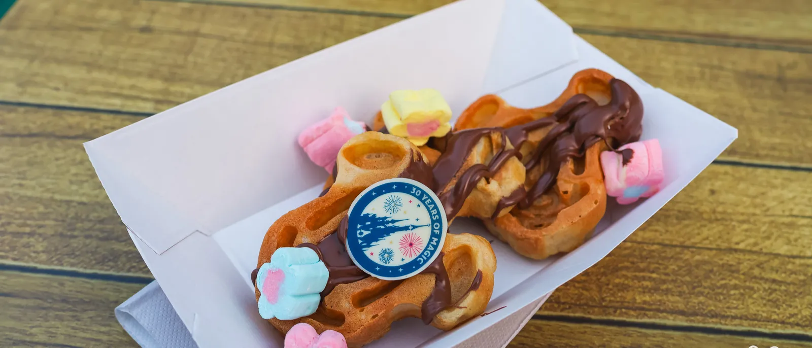 Gaufre en forme de Mickey nappée de chocolat, guimauves fleurs et pique 30 ans, dans une barquette.