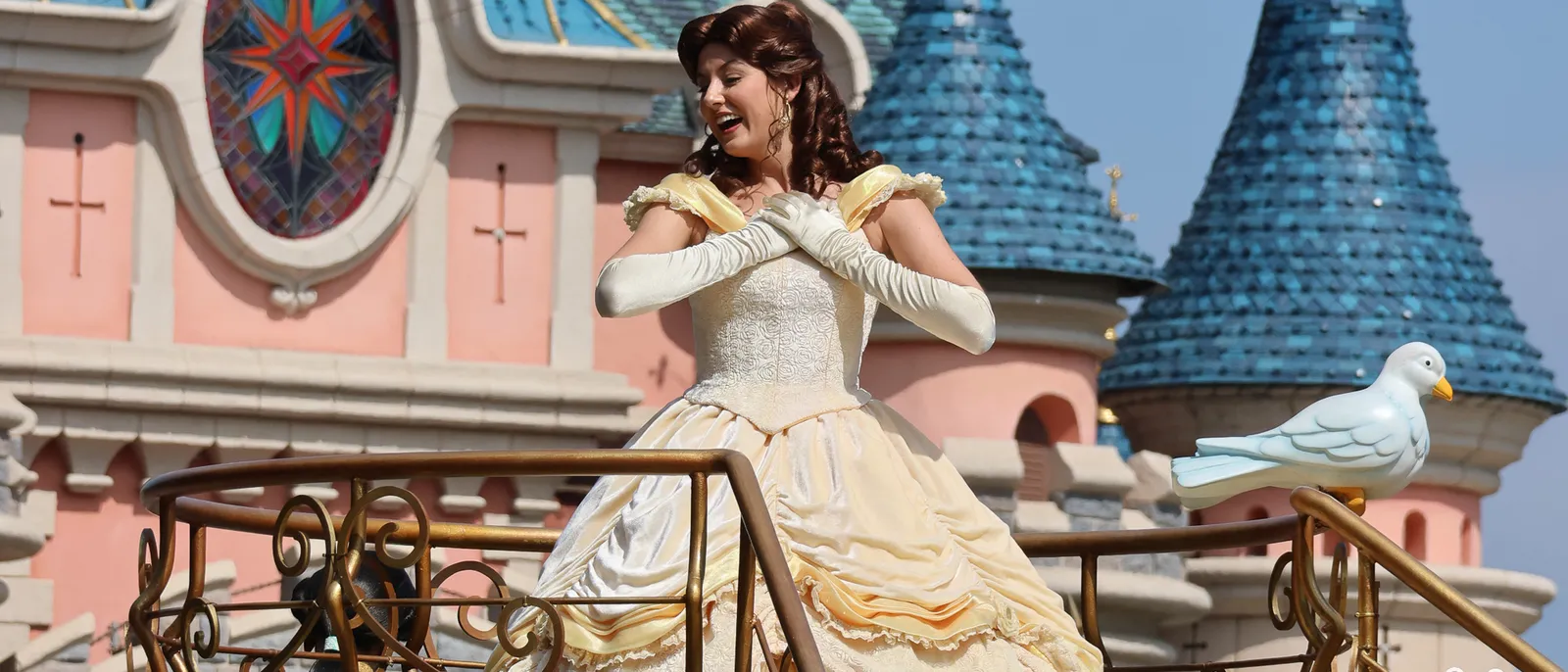 Princesse Belle en robe jaune sur scène devant le château de la Belle au Bois Dormant, colombe blanche